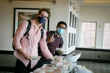 Two students stand at the salad bar grabbing pre-packaged salads.