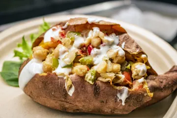Sweet potato stuffed with plant-based toppings and a vegan creamy dressing