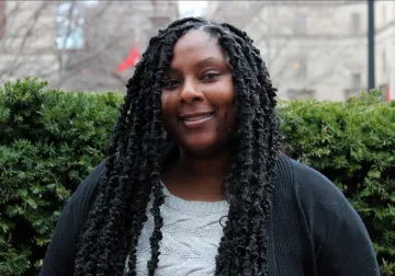 Dionne Douglas photographed on Columbia Campus, green hedges behind