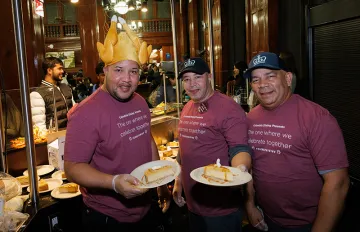 John Jay staff stand at Chef Mike's station holding plates of pumpkin cheesecake