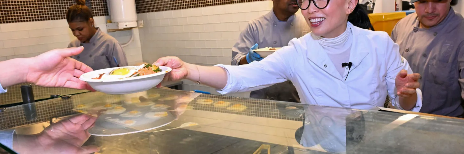 Chef Judy Joo hands students a plate at Wilma's Grill